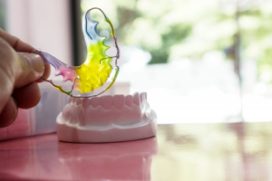 Close up of hand holding a rainbow-colored retainer